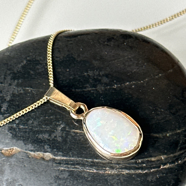 9 carat gold solid opal pendant necklace featuring milky white Coober Pedy opal with colorful sparkles on a gold chain.