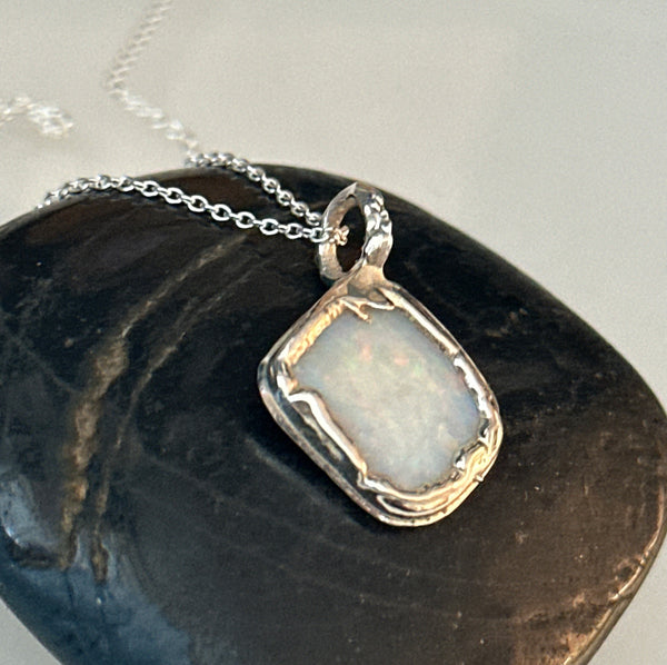 Coober Pedy opal pendant necklace featuring a pale blue opal set in a textured copper and silver setting.