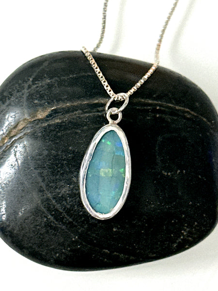 Mintabie opal set in a handmade sterling silver pendant necklace, showcasing vibrant blue and glistening colors.