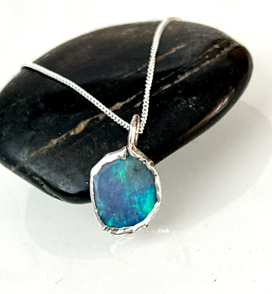 Lightning Ridge opal silver pendant necklace showcasing vibrant blue and green hues on black stone background.