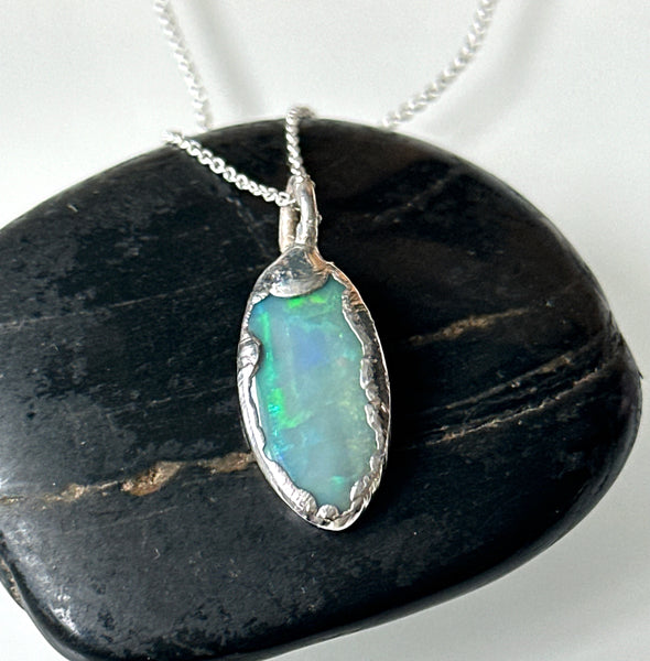 Solid Mintabie opal pendant necklace featuring vibrant blue and green hues, set in a textured silver frame.